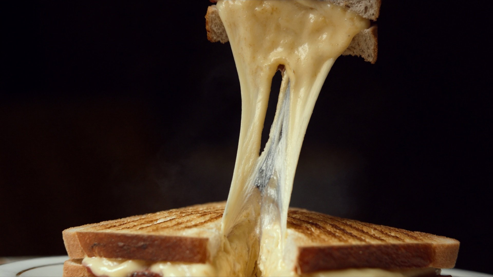 The Classic 4 Cheese toasted melt, cut open with a long molten cheese pull
